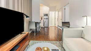 Een moderne woonkamer met een flatscreen televisie, een bank en een eethoek met een tafel en stoelen.