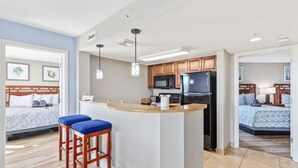 Een moderne hotelkamer met kitchenette, een groot bed en een aparte badkamer.