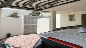 A covered outdoor area with a car parked underneath, a brick wall, and a small window.
