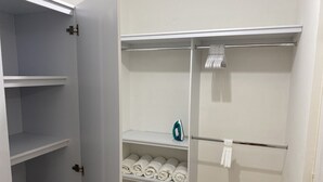 A walk-in closet with multiple shelves, a hanging rod, and a visible iron.