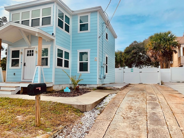 A two-story house with a light blue exterior, a front porch, and a mailbox.