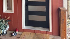 A red wooden door with a black panel and a small decorative horse figure.