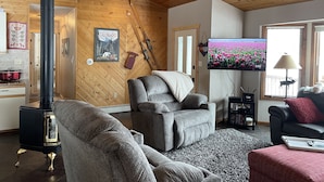 A cozy living room with a fireplace, comfortable seating, a television, and a window with a view of a tulip field.