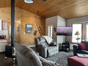 Una sala de estar acogedora con chimenea, asientos cómodos, televisor y ventana con vistas a un campo de tulipanes.