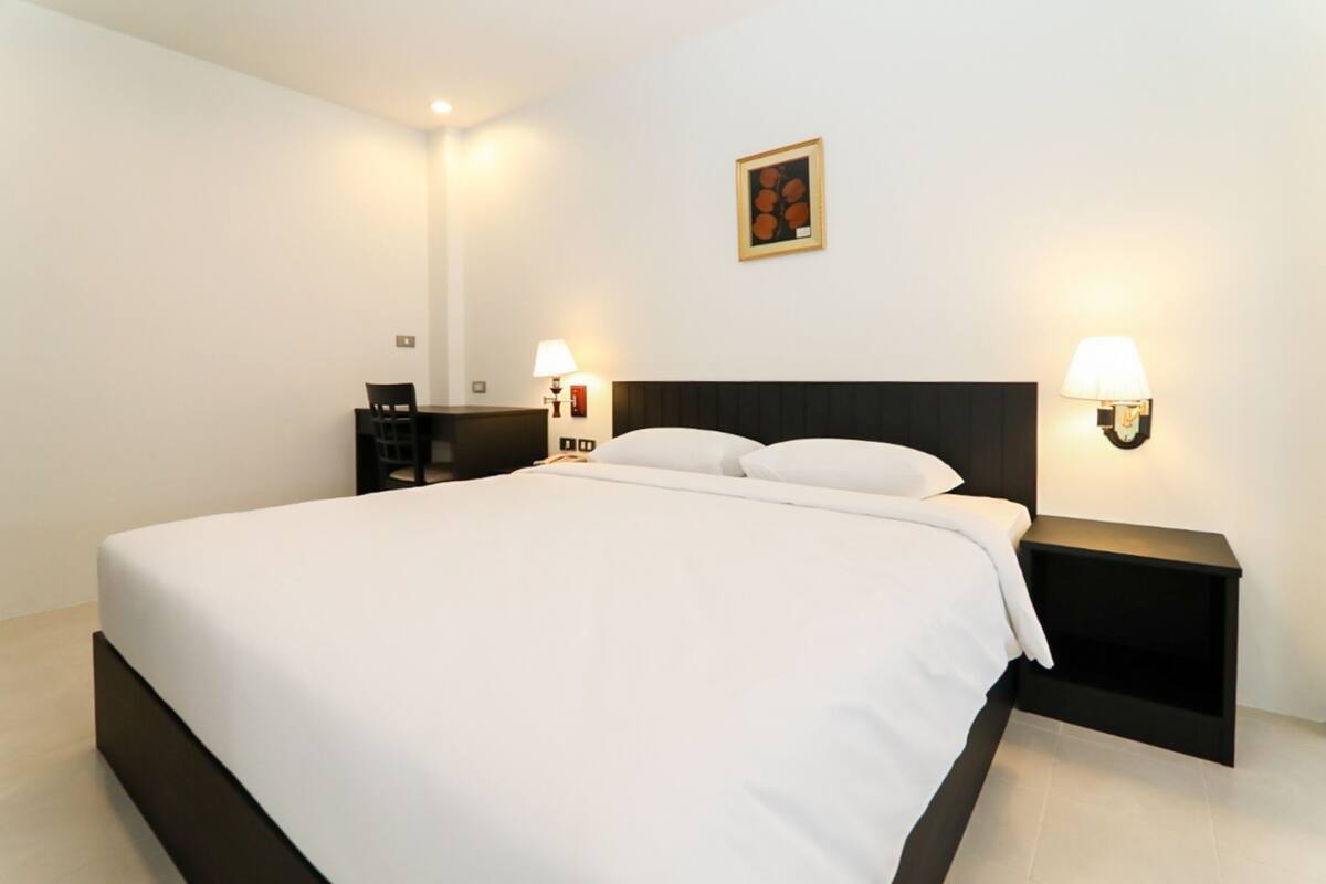 A modern hotel room with a large bed, bedside tables, and wall-mounted lamps.