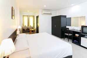 A hotel room with a bed, a desk with a computer, a television, and a wardrobe. - G House Hotel (Hua Hin)