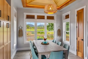 Uma sala de jantar com uma mesa grande, cadeiras e vista para um campo de golfe por grandes janelas.