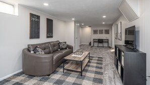 A modern living room with a leather sofa, a coffee table, and a TV stand. - Five Star Flip- Bright & Renovated 3BR/2BA (Sioux Falls)