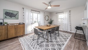 A modern kitchen with a wooden table, bar stools, and a ceiling fan. - Five Star Flip- Bright & Renovated 3BR/2BA (Sioux Falls)