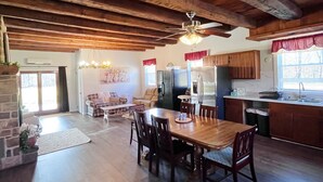 A spacious living area with a wooden dining table, chairs, and a fireplace. There is a kitchen area with cabinets and a refrigerator. - The River House: stone section built in 1790, borders the scenic Juniata  River! (Mifflintown)
