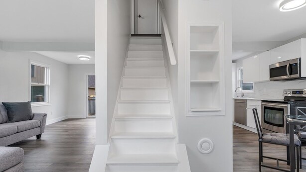 Un interior moderno con una escalera, una cocina y una sala de estar.