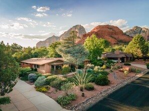 A house with a patio, surrounded by various plants and trees, with mountains in the background. - Sedona Serene Retreat, Amazing Views & Hot Tub! Walk to Hiking Trails!  (Sedona)