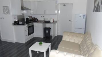 A compact living space with a kitchenette, a sofa, and a small table.