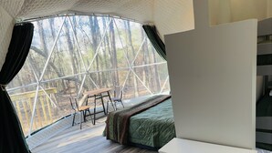 Una habitación acogedora con un ventanal grande, una mesa de madera, dos sillas, una cama y una chimenea.