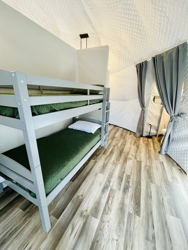 Dormitorio con literas, suelo de madera y techo blanco con textura.