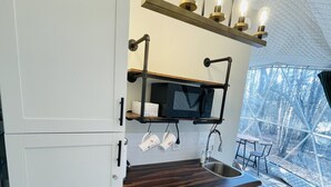 Cocina compacta con microondas, un lavabo y cafetera. Hay armarios y una encimera.