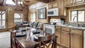 A wooden cabin interior with a dining table set for four, a microwave, and a sink in the kitchen area. - Hideaway Hangout! Family Retreat! Beautiful views, 3 decks, hot tub, multicade! (Sevierville)