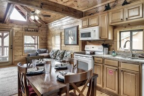 A wooden cabin interior with a dining table set for four, a microwave, and a sink in the kitchen area. - Hideaway Hangout! Family Retreat! Beautiful views, 3 decks, hot tub, multicade! (Sevierville)