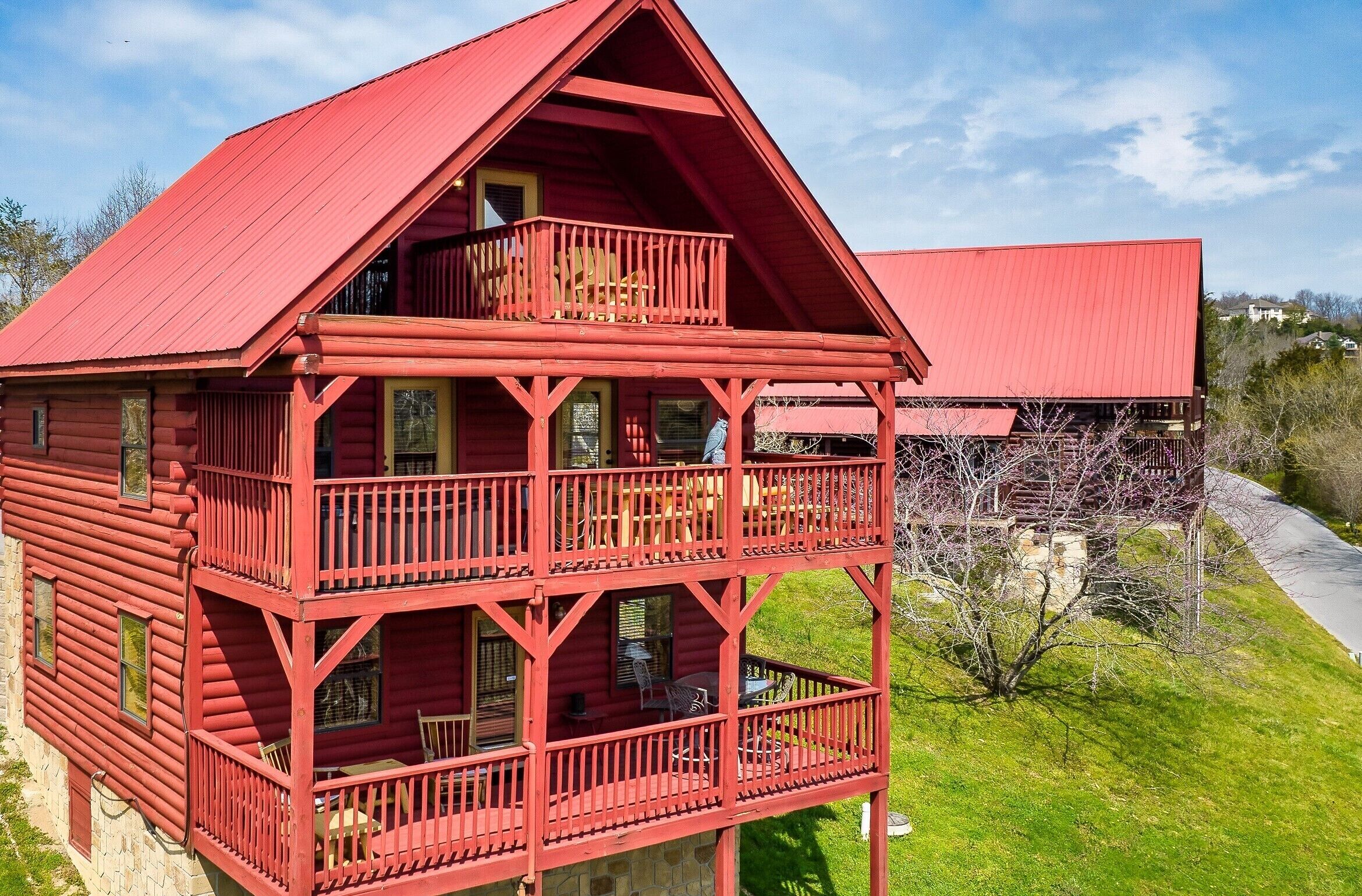 A red wooden cabin with a balcony and a separate section with a red roof.