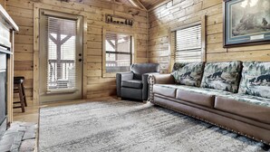 A log cabin interior with a fireplace, a leather sofa, and a framed picture on the wall. - Hideaway Hangout! Family Retreat! Beautiful views, 3 decks, hot tub, multicade! (Sevierville)