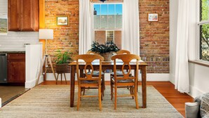 Un coin repas avec un mur en briques, une table en bois et des chaises.