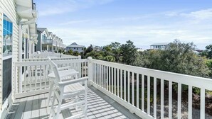 A wooden deck with white railings and a white chair, overlooking a residential area with houses and trees. - Our Place On 30a (Santa Rosa)