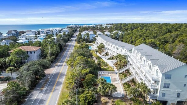 A coastal residential area with a row of white houses, a swimming pool, and a view of the ocean. - Our Place On 30a (Santa Rosa)