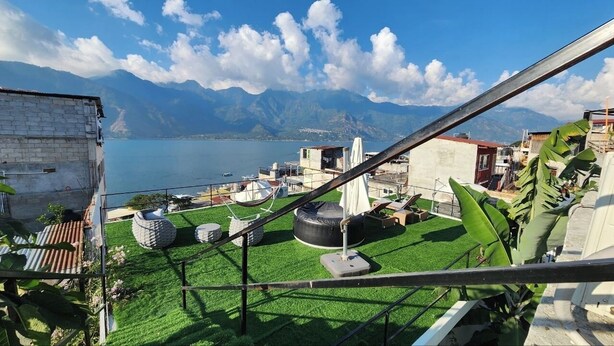 Eine Dachterrasse mit künstlichem Rasen, Blick auf einen See, Berge und einen klaren Himmel.