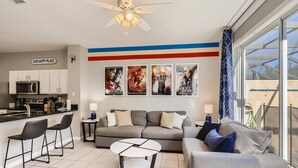 A modern living room with a sofa, two armchairs, a coffee table, and a kitchen area with a microwave and cabinets.
