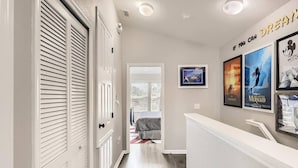 A hallway with a white door, a bed in the background, and movie posters on the wall.