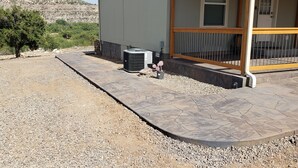 Een gebouw met een patio van natuursteen, een airconditioner en een klein decoratief plantje.