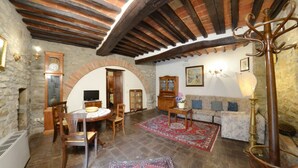 A traditional room with stone walls, a wooden ceiling, a round table with chairs, a sofa, and a lamp. - San Pietro Ortensia - Apartment with swimming pool (Cortona)