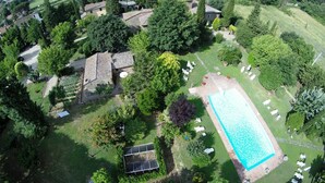 Vue aérienne d’un quartier résidentiel avec une piscine, des panneaux solaires et un jardin.