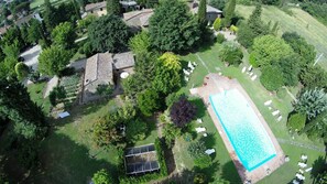 Vue aérienne d’un quartier résidentiel avec une piscine, des panneaux solaires et un jardin.