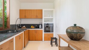 Uma cozinha compacta com armários de madeira, bancada de granito, liquidificador e uma tigela de cerâmica grande sobre uma mesa de madeira.
