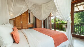 A bedroom with a canopy bed, a balcony with a view of greenery, and a wooden wardrobe. - Villa Aloui by Villa Finder (Kerobokan)