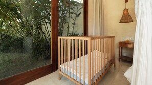 A wooden crib with a view of bamboo outside a window. - Villa Aloui by Villa Finder (Kerobokan)