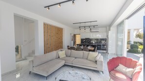 A modern living room with a sectional sofa, a round marble coffee table, and a pink armchair.