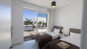 A hotel room with two beds, a large window, and a view of palm trees.