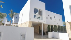 A modern two-story building with a flat roof, large windows, and a stone base.