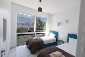 Een moderne hotelkamer met twee bedden, een groot raam en uitzicht op de omgeving.