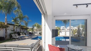 A modern outdoor living area with a pool, lounge chairs, and a red chair.