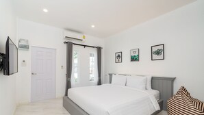 Un dormitorio moderno con una cama grande, un televisor de pantalla plana en la pared y una ventana con cortinas.