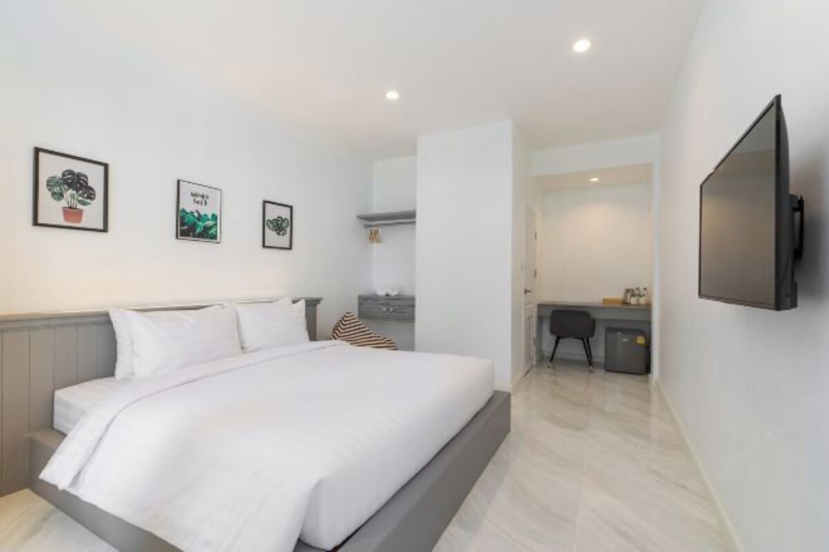 A modern hotel room with a bed, a desk, and a flat-screen TV.