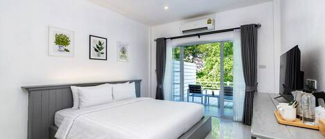 Una habitación de hotel moderna con una cama grande, un escritorio con cafetera y vistas a zonas verdes.