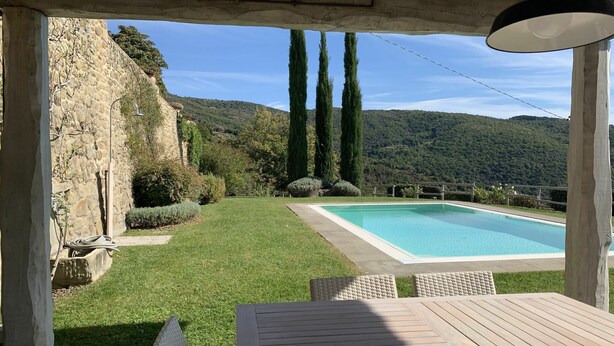 A wooden deck with a pool, stone walls, and a view of the mountains. - Villa in Cortona with 3 bedrooms sleeps 8 (Cortona)