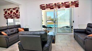 Ein modernes Wohnzimmer mit zwei Ledersofas, einem Glastisch und einer Wanddeko mit Muster.