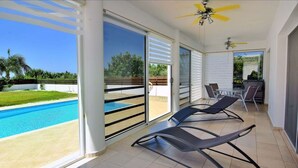 Un balcón con piscina, sillas de tomar el sol y una mesa con sillas.