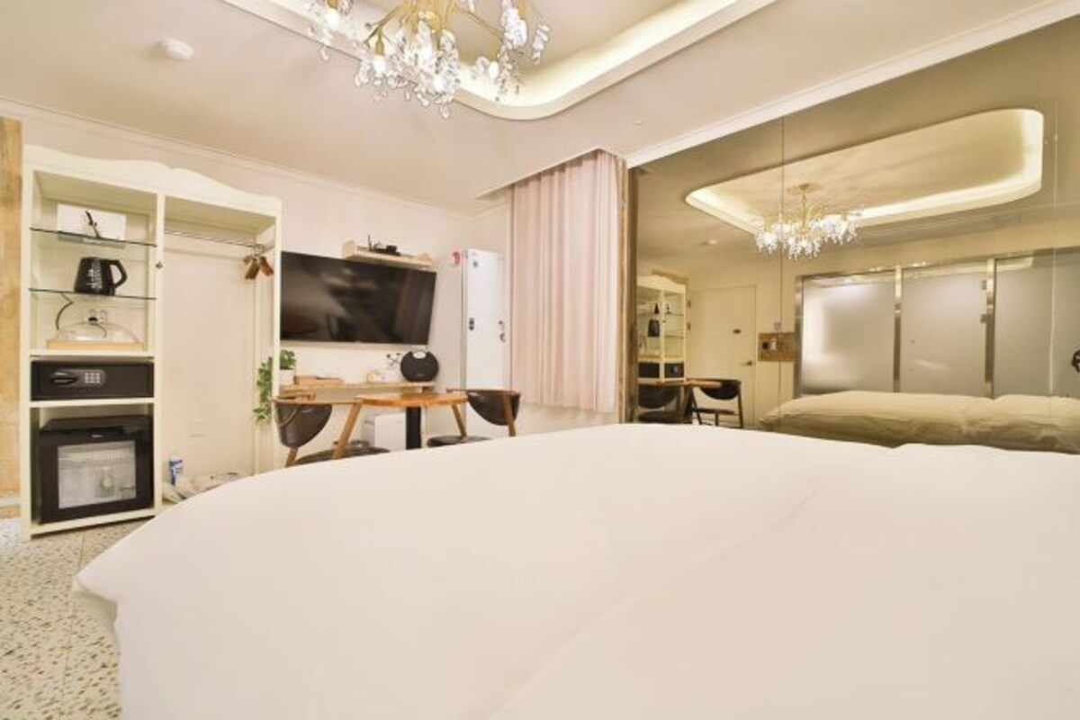 Una habitación de hotel moderna con una cama grande, televisión, escritorio y armario.
