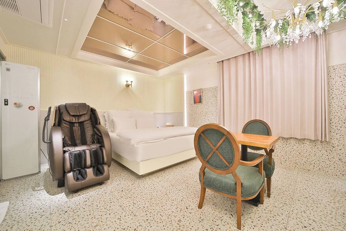 A modern room with a massage chair, a sofa, and a dining table with chairs.
